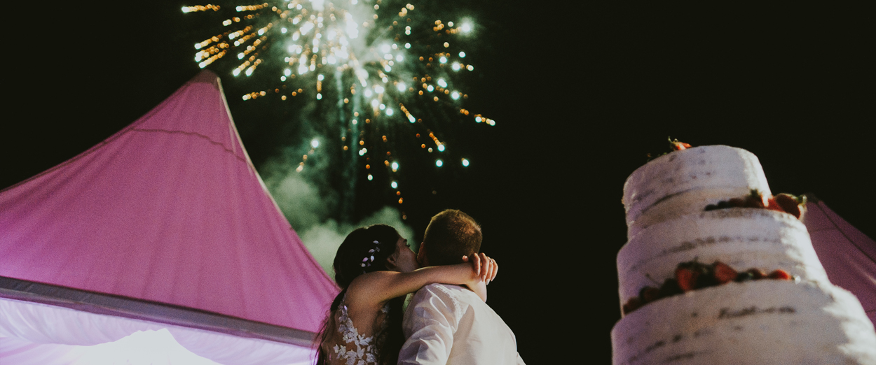 A couple outside of their marquee wedding watching fireworks