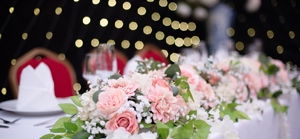 A close up of a wedding top table with fairy lights in the background