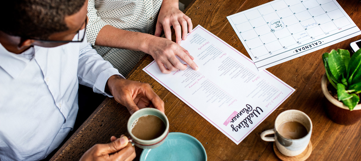A couple sat at a coffee house planning their wedding