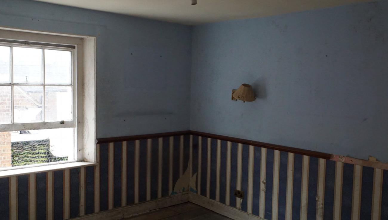 Corner of the Judge Kay room before restoration, showing the dado rail and windows
