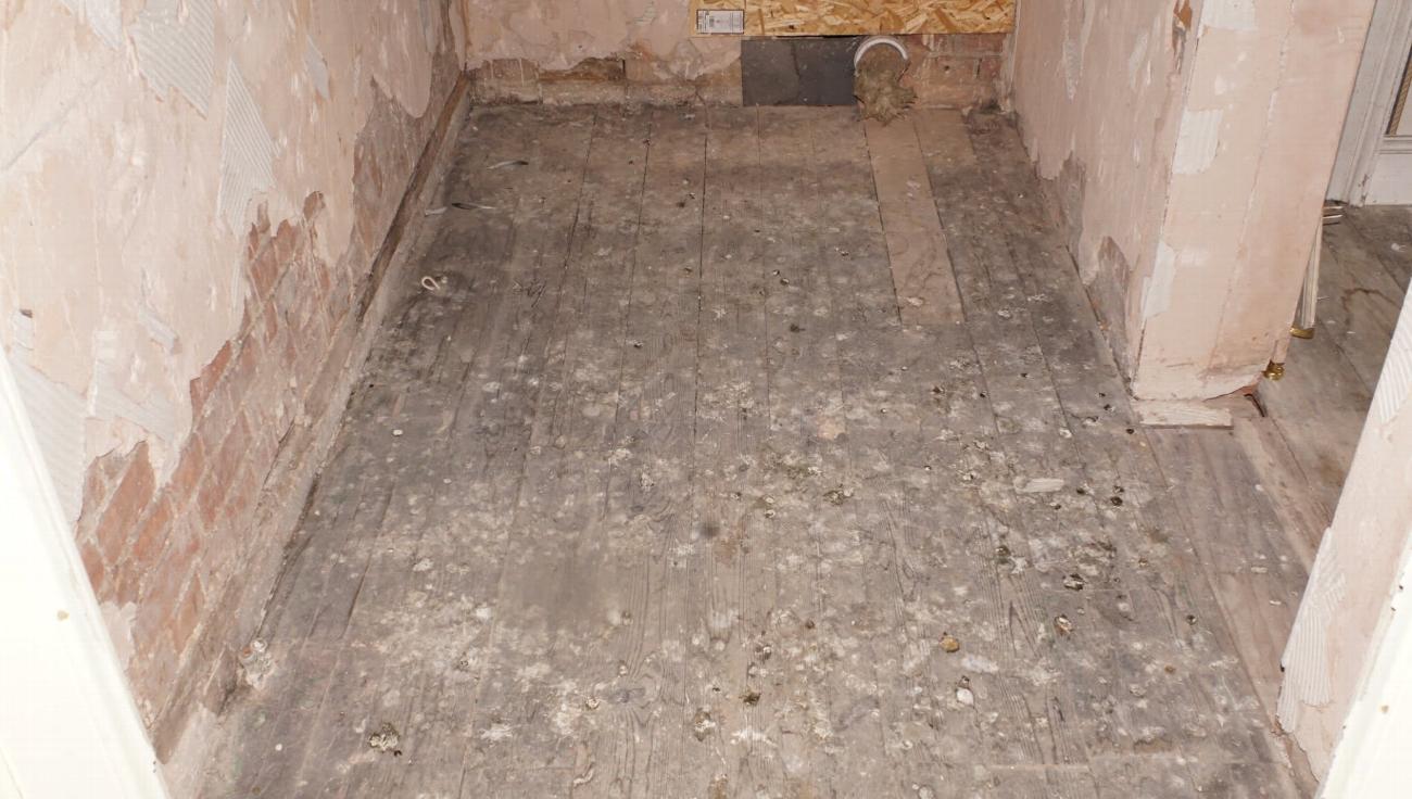 Bare floor and stripped walls in the Judge Kay room before restoration