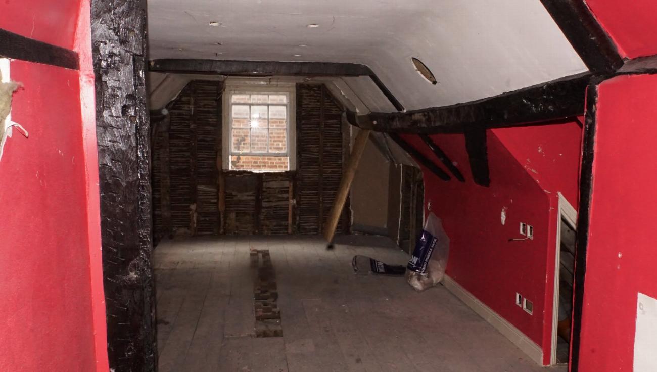 Exposed timbers and bare floor in the Judge Rigby room before restoration
