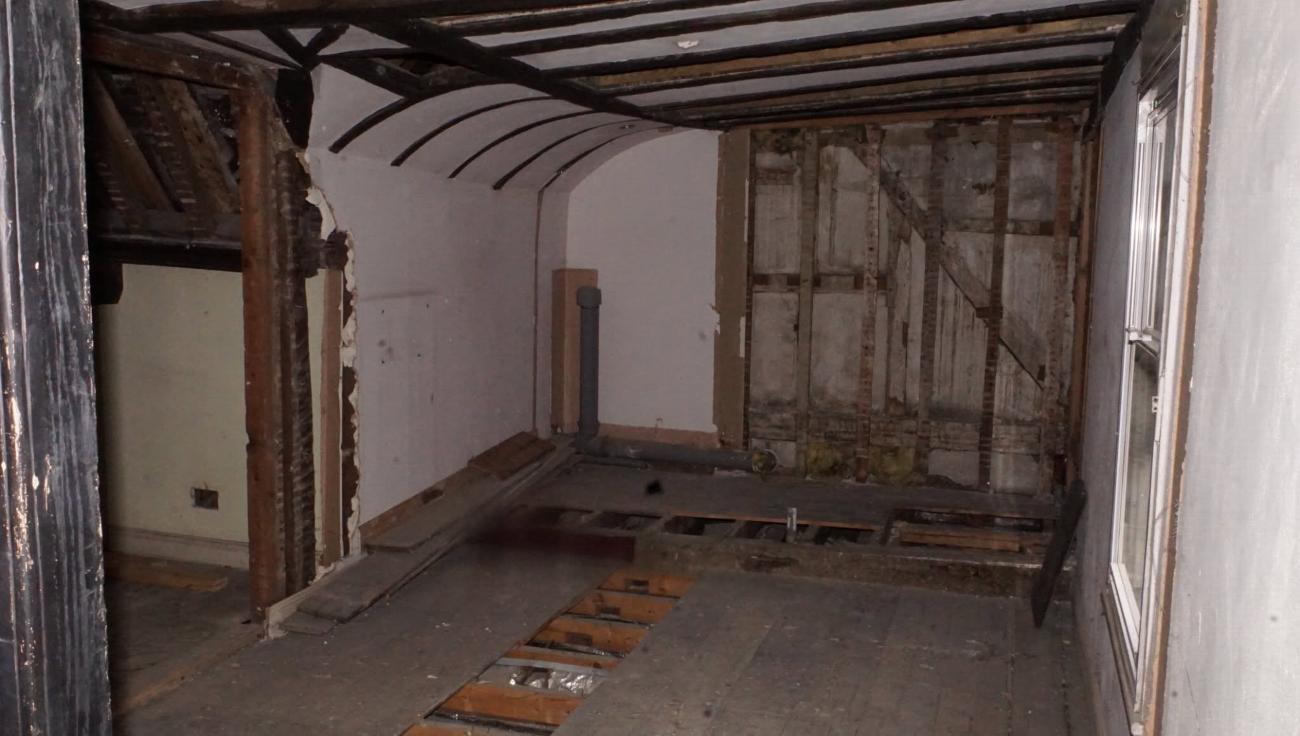 Bare walls and open framing in the servants' quarters before restoration